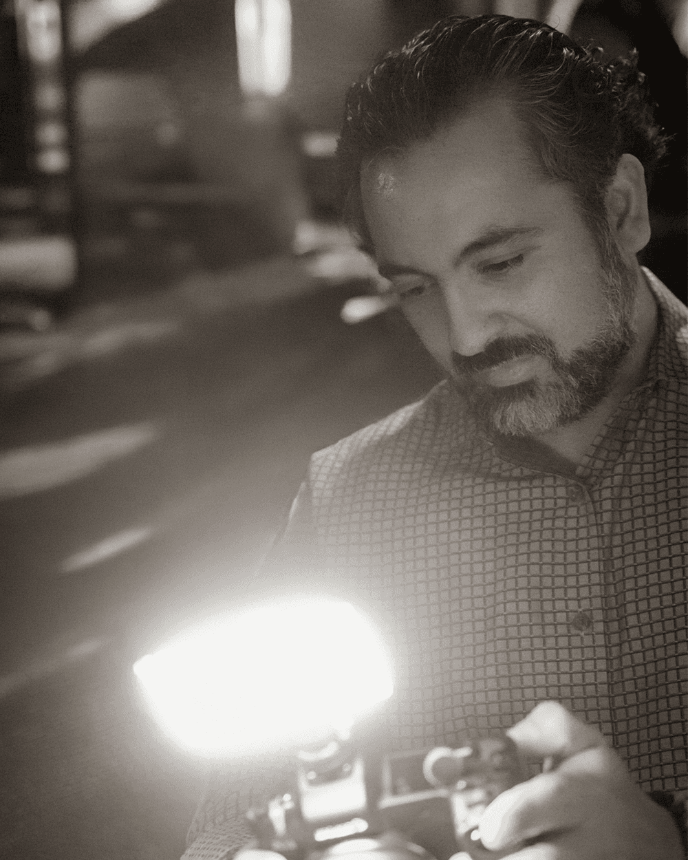 Black and white portrait of Al Vega holding a camera